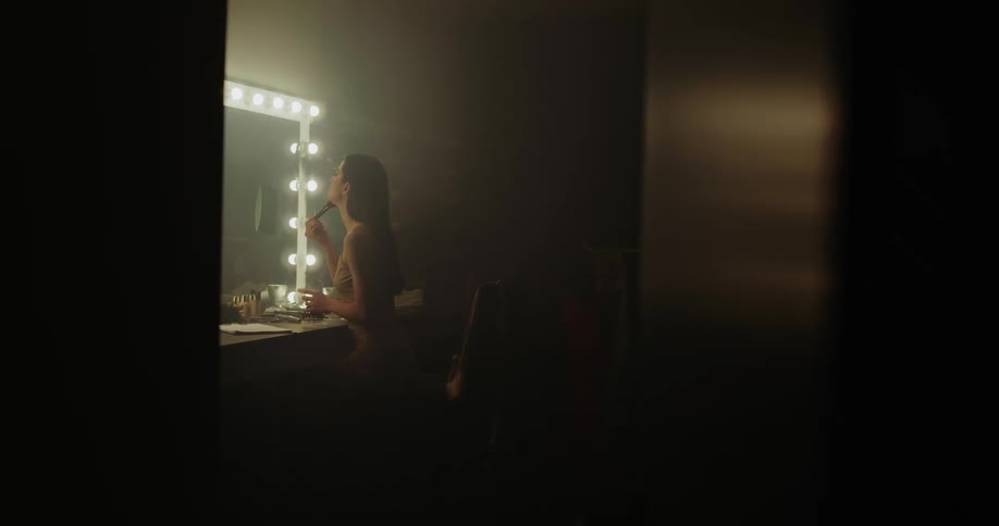 A woman in a dressing room applies make up