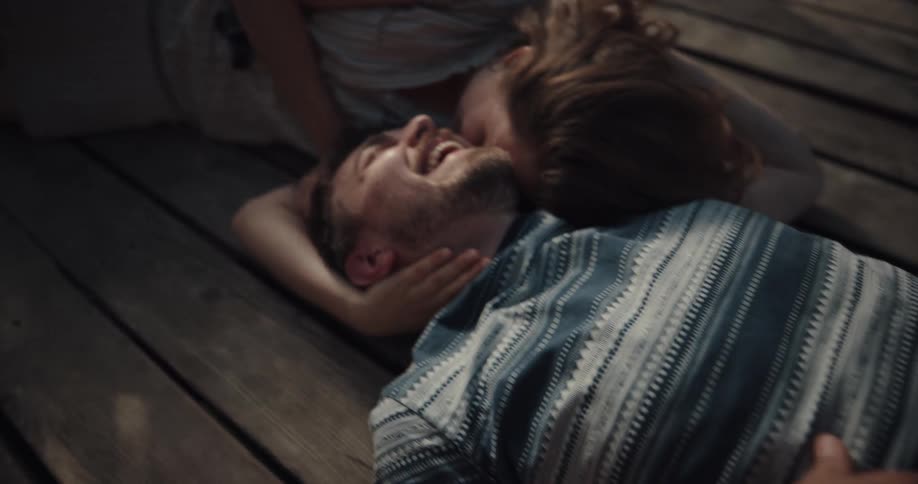 A man and woman are laying outdoors on a deck