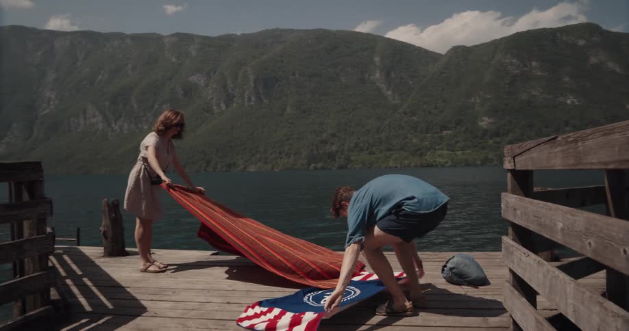 Couple runs on pier and lays towels and takes off clothes two swim