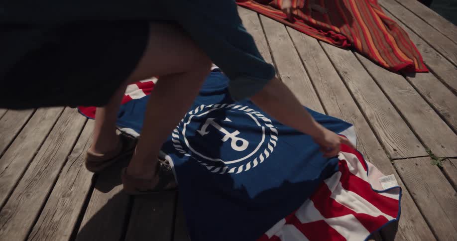 A man and woman race to the end of a lake pier and put their towels on the edge
