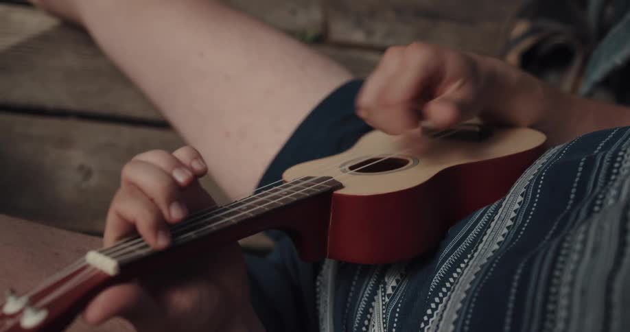 A person is playing the ukulele while sitting