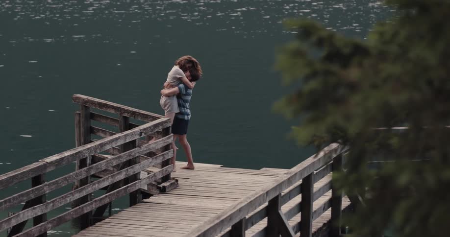 Husband and wife are sitting on the dock by the lake