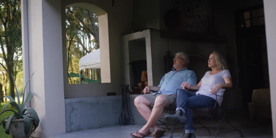 A man and woman sit on their porch together relaxing