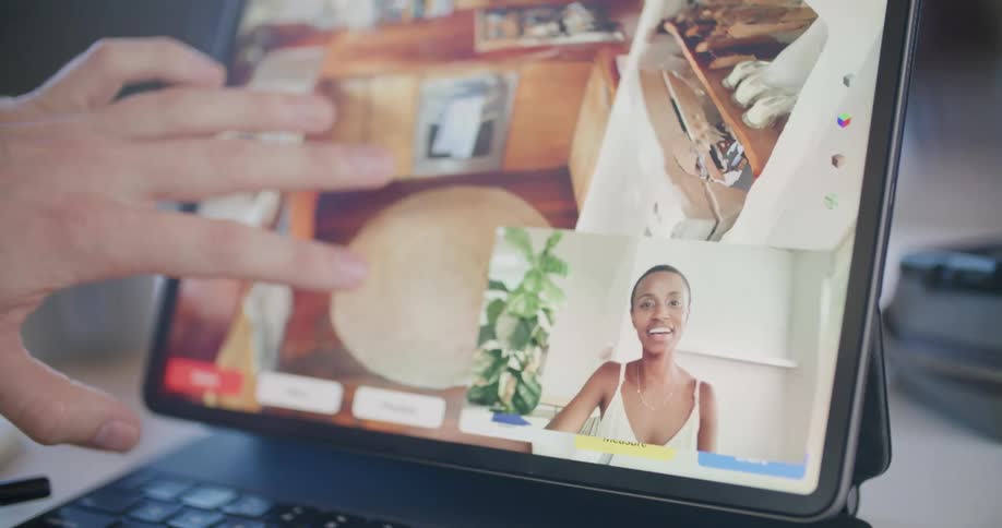 A man uses a split screen on his tablet to talk to a woman via video call and to look at images of a kitchen