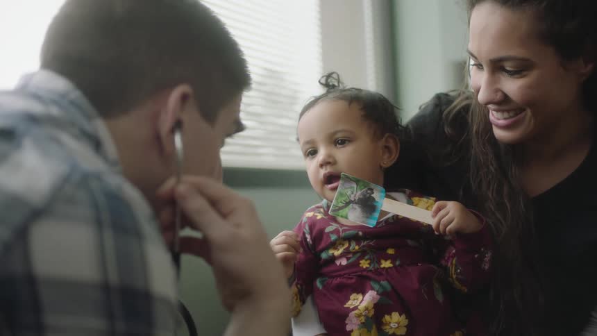 A doctor shows his stethoscope to a little girl to put her at ease