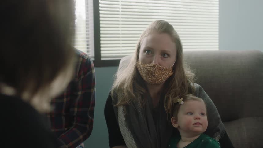 A woman holds an infant baby in a doctor office