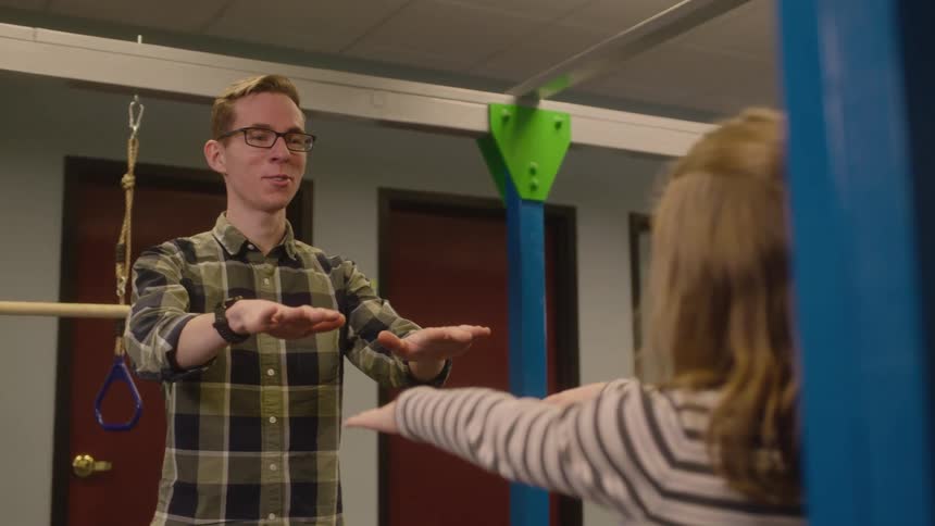 A man and a woman in a room stretching with a wall and doors in the background