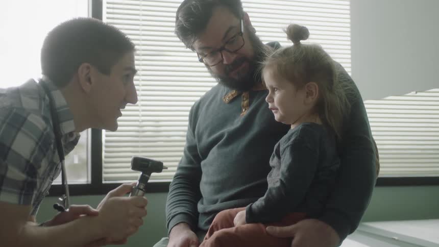 A man a girl and a doctor in a clinic with a window in the background