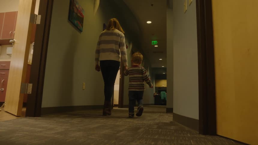 A mother and son walking down a hallway