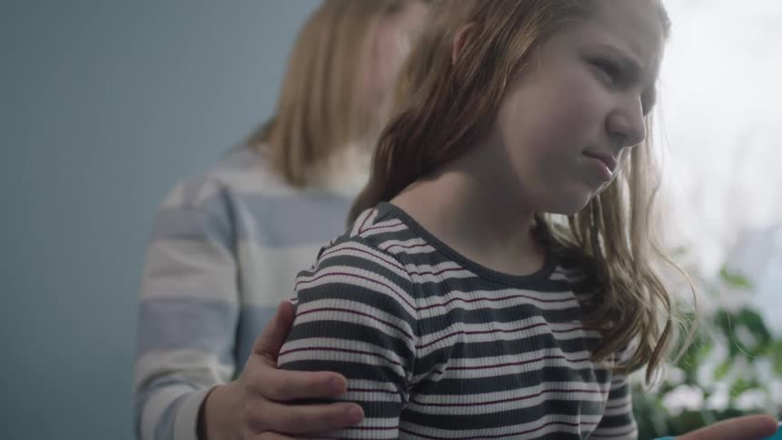 Blonde mother caresses sad daughters shoulder