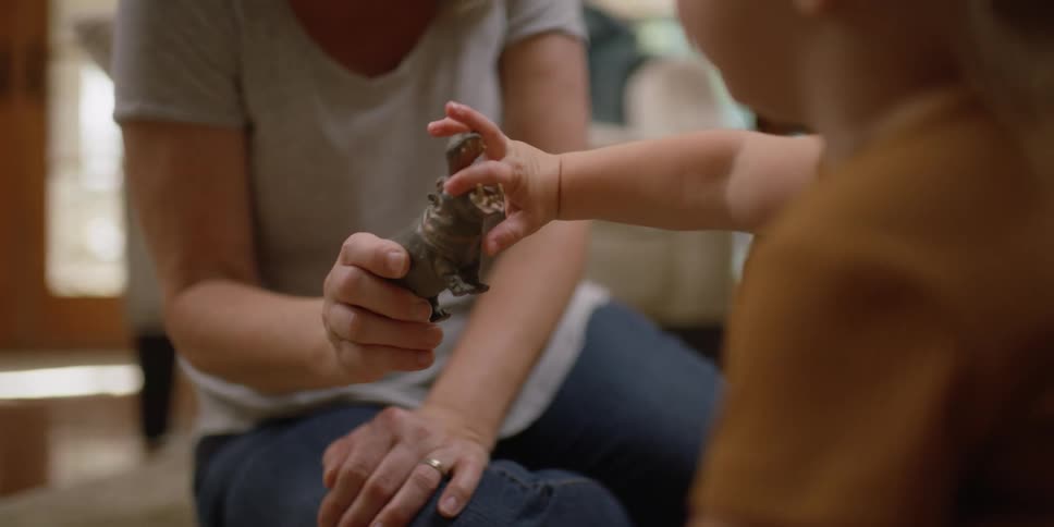 A woman sits on the floor and play with a young toddler
