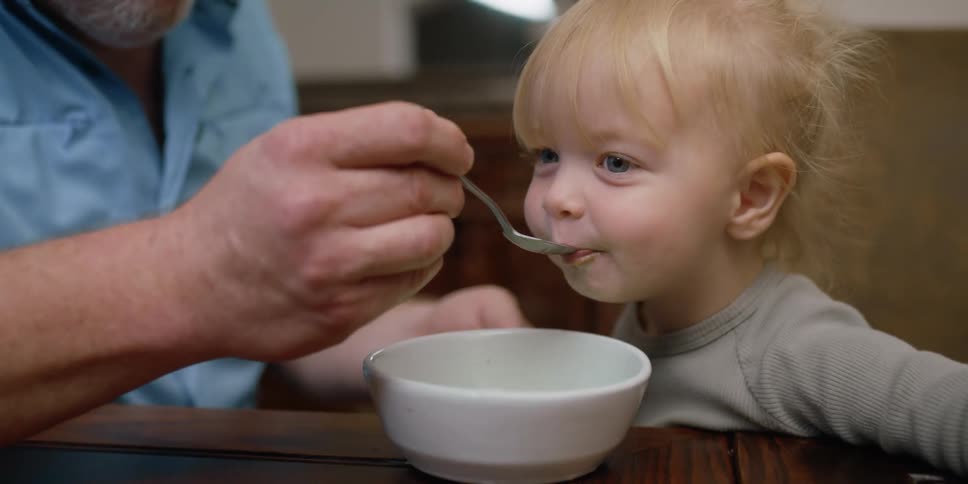 A man feeds a child from a bowl