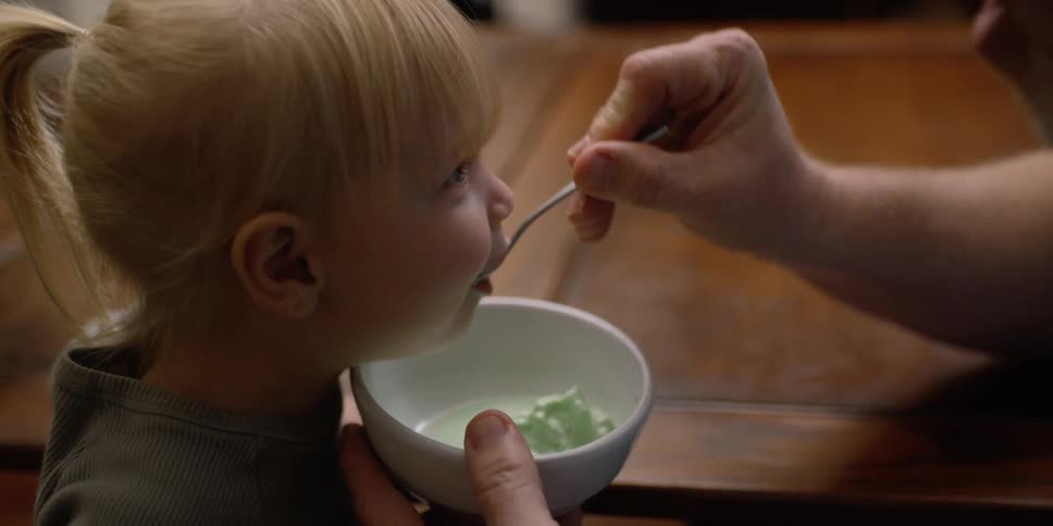 A man feeds ice cream to a child