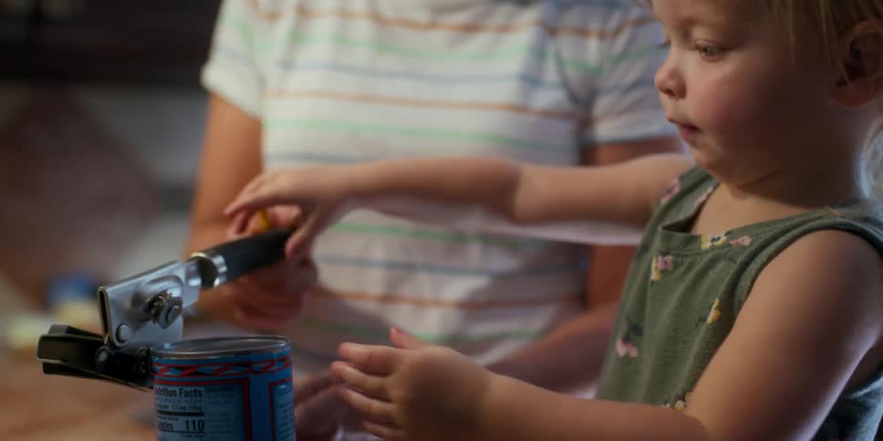 Blonde grandmother with glasses help granddaughter open can in the kitchen