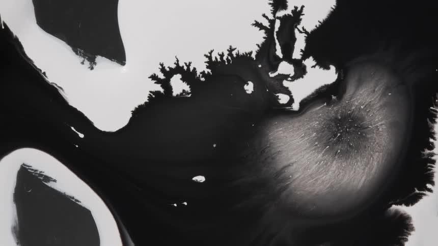 Black ink spreads over a white surface