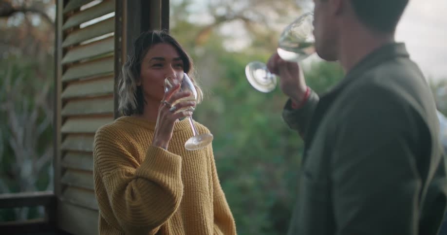 Man and woman grin and clink glasses in a toast before drinking wine