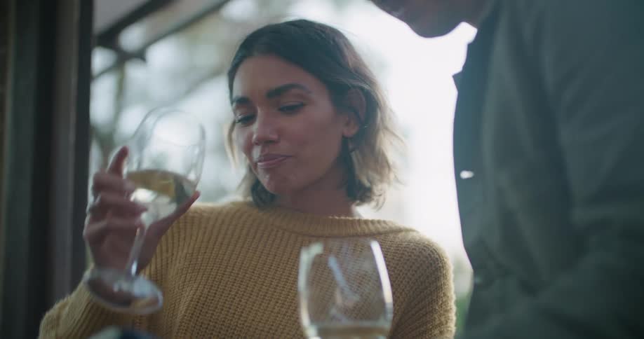 A woman shakes her head and talks after taking a sip of wine