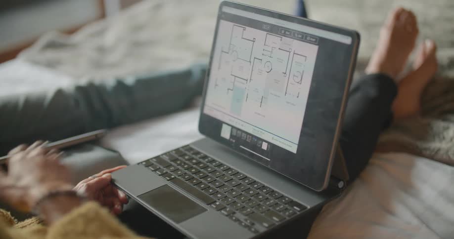 Two people sitting in bed looking at floorplans on an ipad