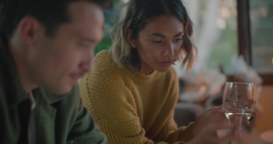 Couple sits drinking wine and talking while viewing computer screen