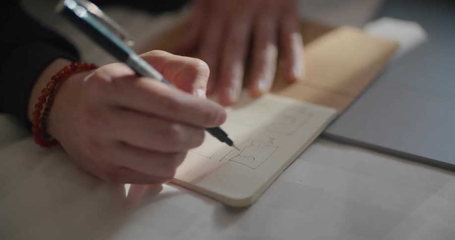 A man holding a pen sketching a diagram and writes in the labels
