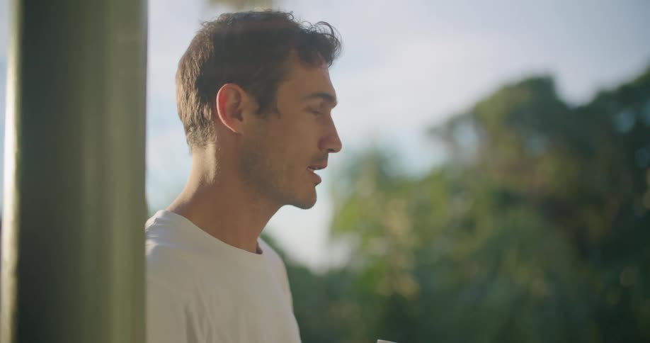 A man is drinking from a mug outside