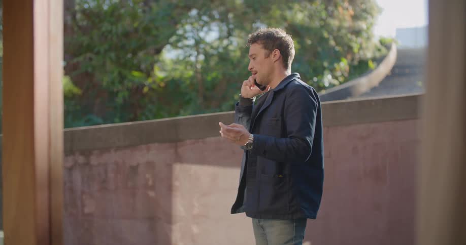 A man gestures with his hands while standing out and talking on the phone
