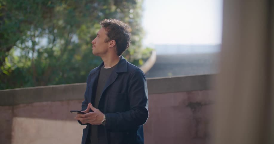 A man stands outside on his patio while looking at this smart phone