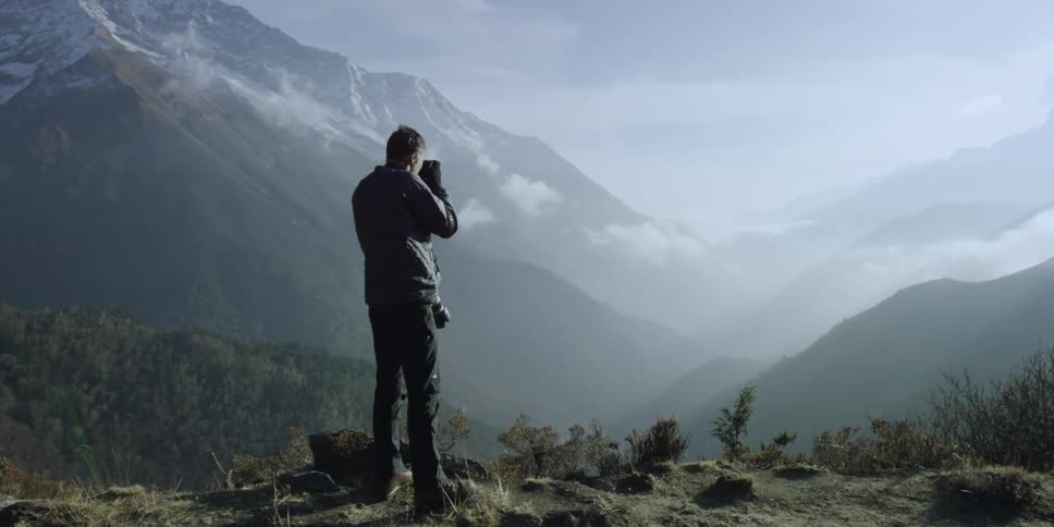 A man is on the edge of a cliff taking photographs