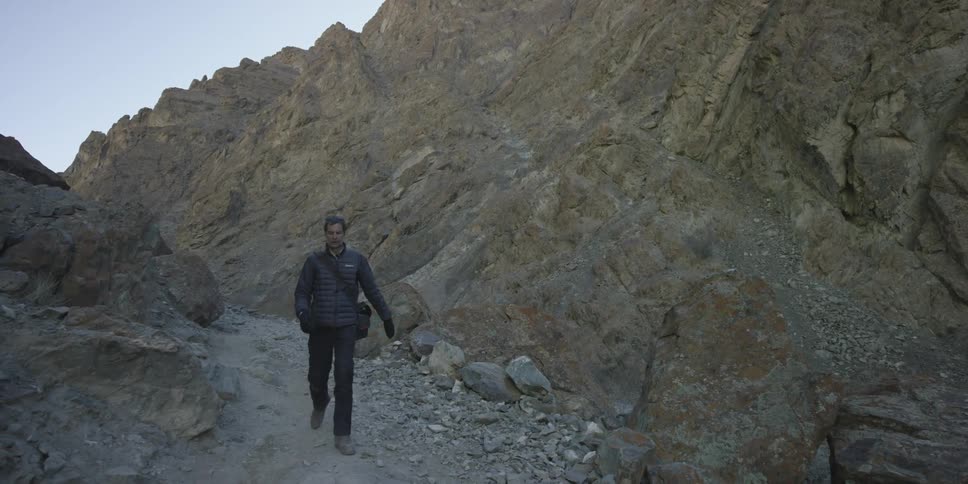 A man is walking down a rocky canyon