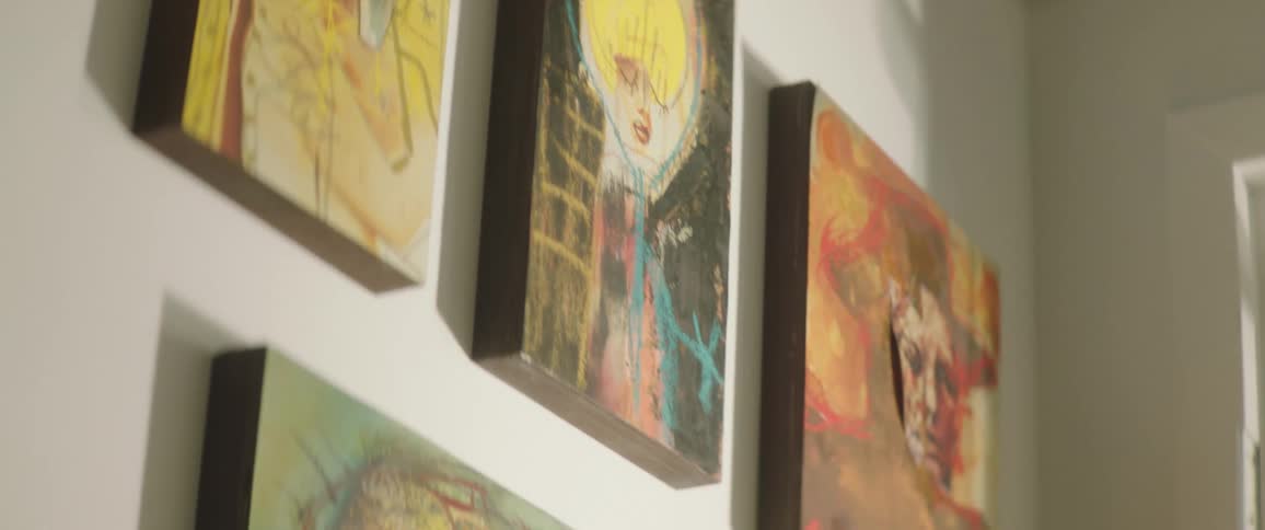 Mid sized painted canvases hang on wall