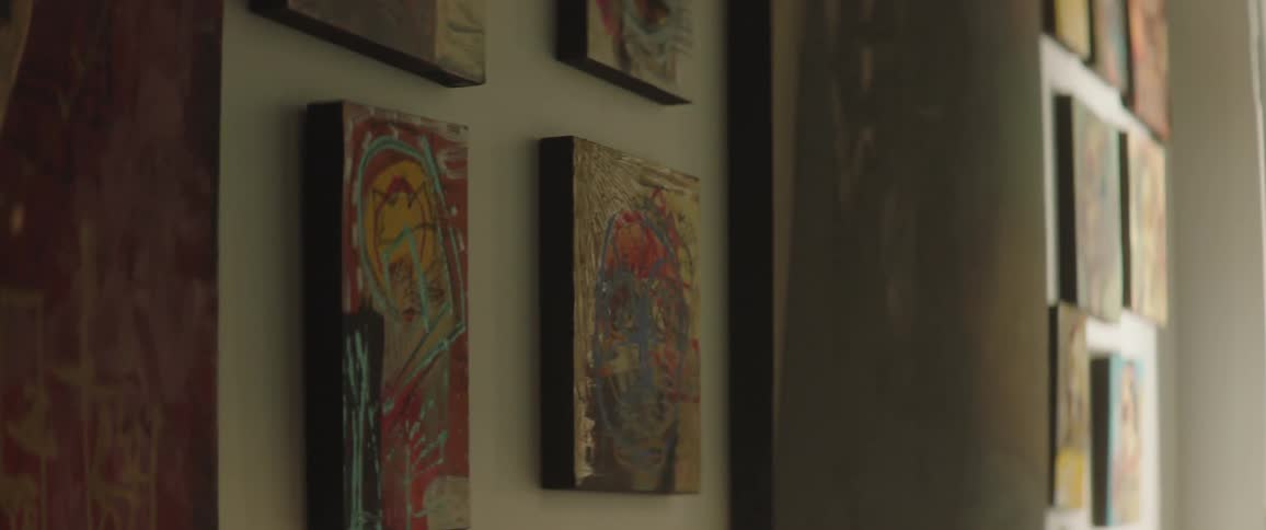 A wall covered with small and large pieces of unframed artwork