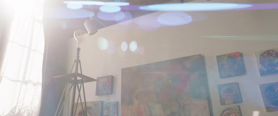 Colorful matching paintings of varying size cover a wall in an art gallery