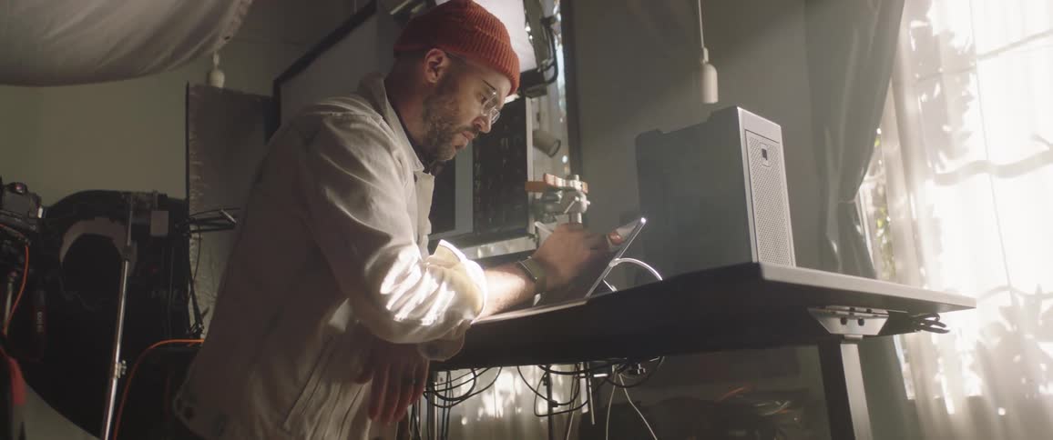 A man with a hat in a studio using a tablet with a stylus