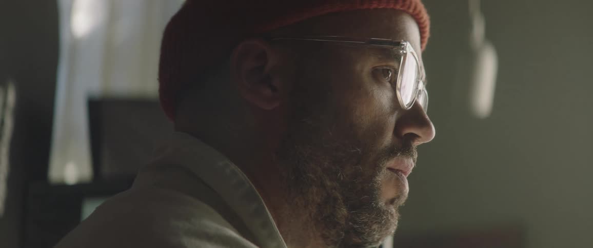 A man with a hat and glasses using a tablet with a stylus