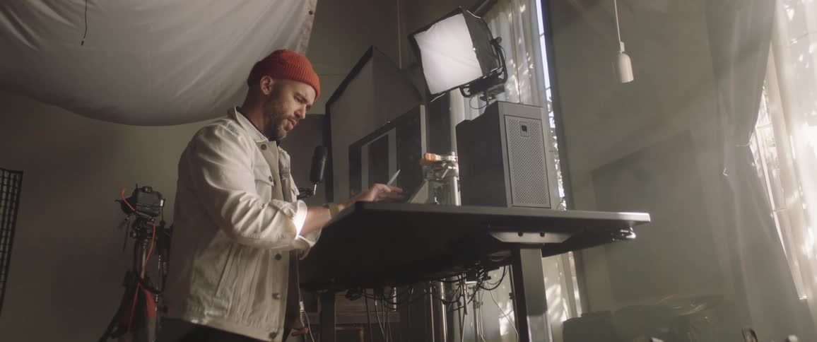 A man works on a computer with a photography light in front of him