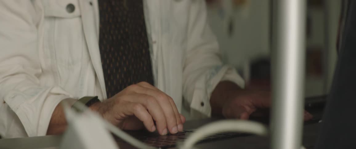 A man uses the trackpad on a laptop as he works at a standing desk