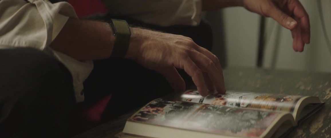 Man wearing glasses reading a book over a coffee table