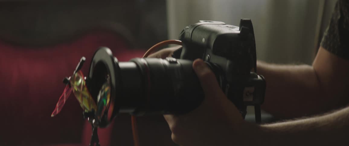 A photographer looks over his camera with a large lens