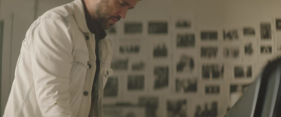 A man lets a large piece of paper with artwork come out of an oversized printer