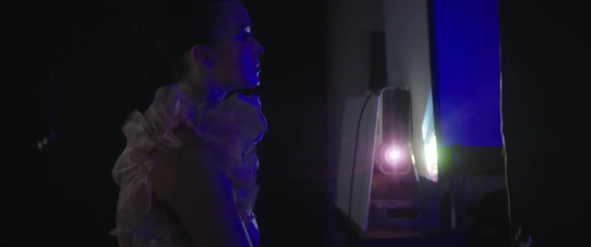 Fashion model wearing outfit with ruffles poses under colored lights