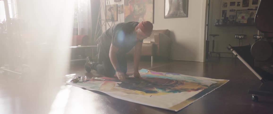 A man painting on a canvas on the floor