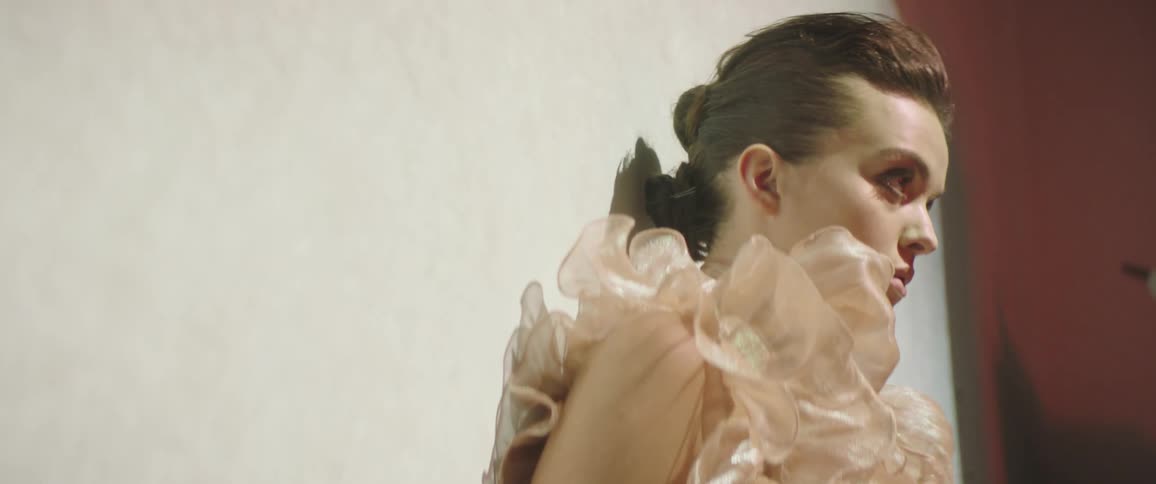 Fashion model wearing outfit with ruffles poses against wall