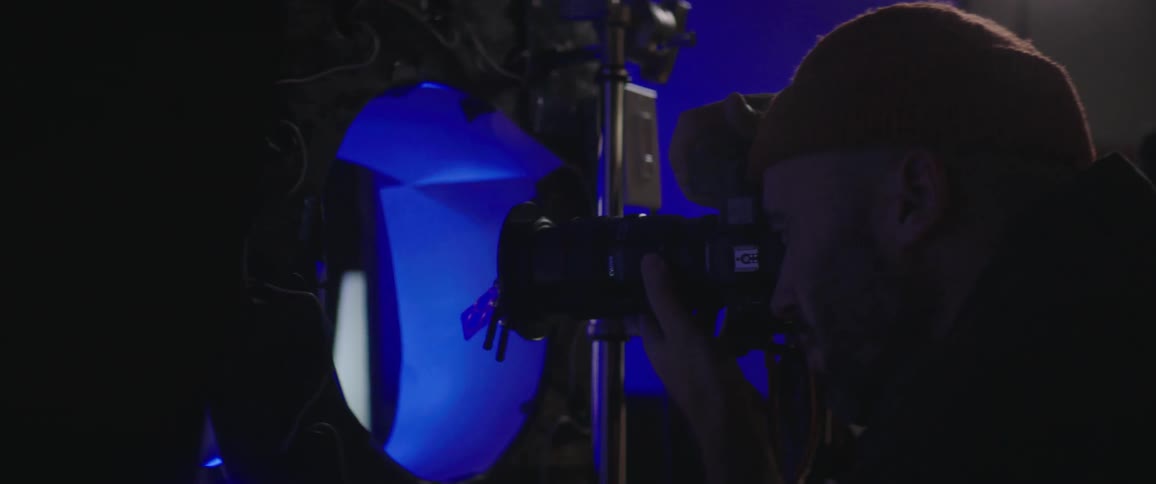 Photographer takes picture of fashion model posing under colored lights as monitor shows images