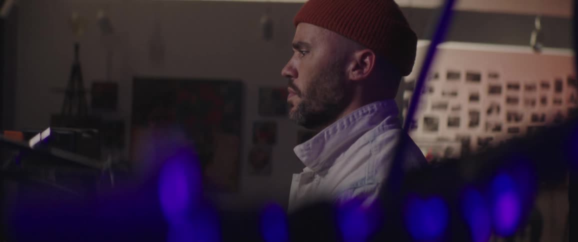 Man with woolly hat a beard and a white jacket works on desktop in the studio