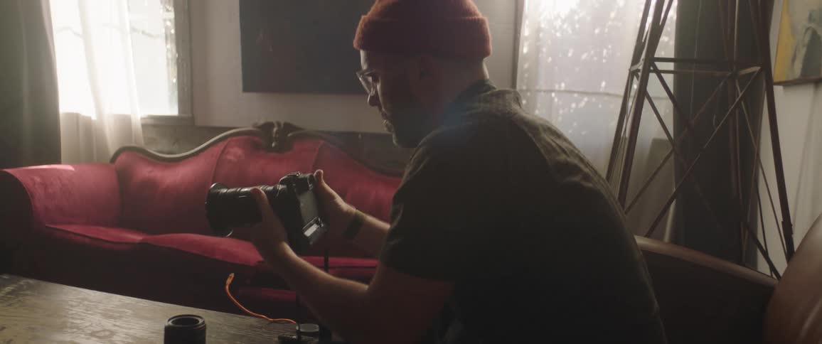 A male photographer sits down and inspects his digital camera