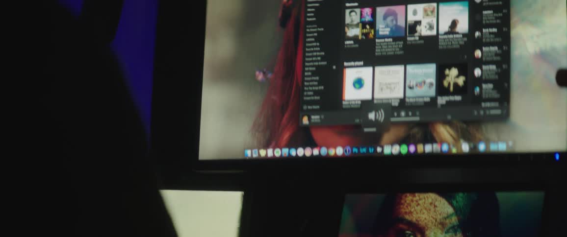 Graphic designer working on multiple screens inside a dimly lit office