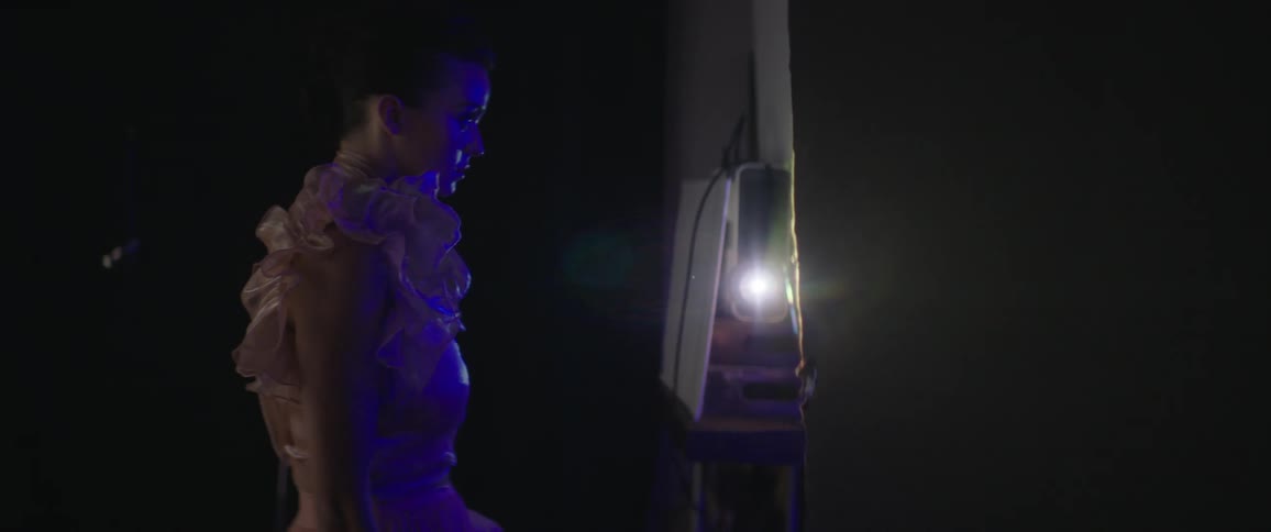 Fashion model poses under colored lighting as camera flashes
