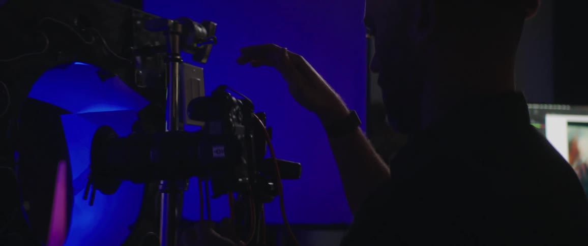 Man wearing a toque adjusts a camera that is attached to a stand