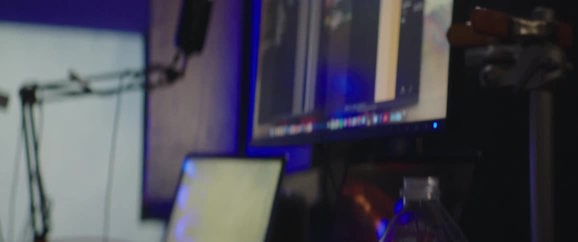 A person sits at a desk with a large computer and laptop setup