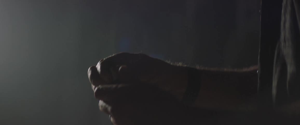 Older man with beard works with his hands in dimly lit room